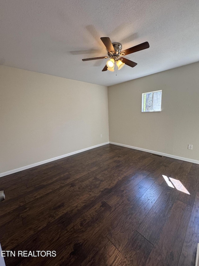 unfurnished room with dark wood-type flooring, ceiling fan, a textured ceiling, and baseboards