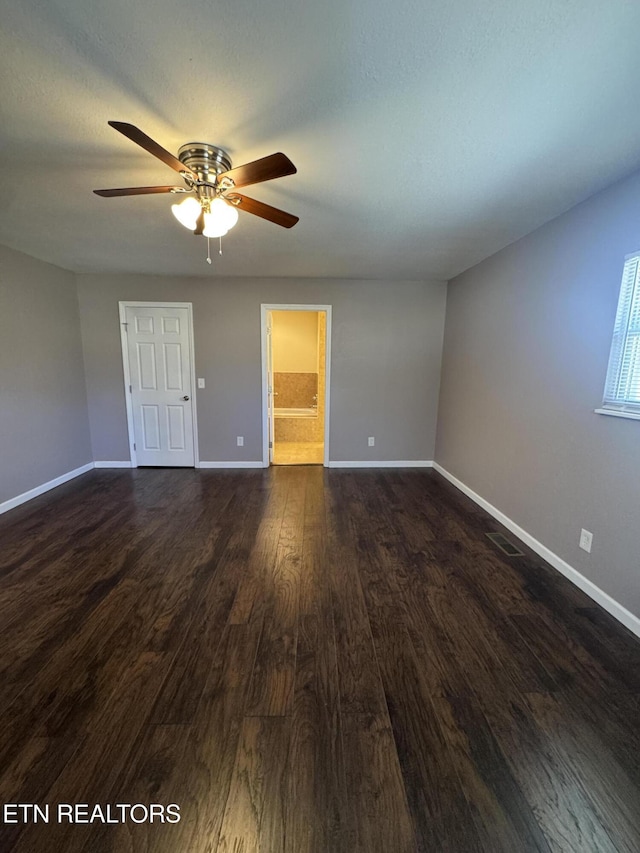 unfurnished room featuring dark wood-style floors, visible vents, baseboards, and a ceiling fan