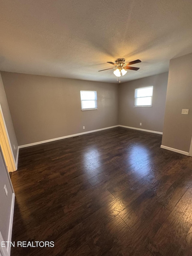 unfurnished room with dark wood-type flooring, a textured ceiling, baseboards, and a ceiling fan