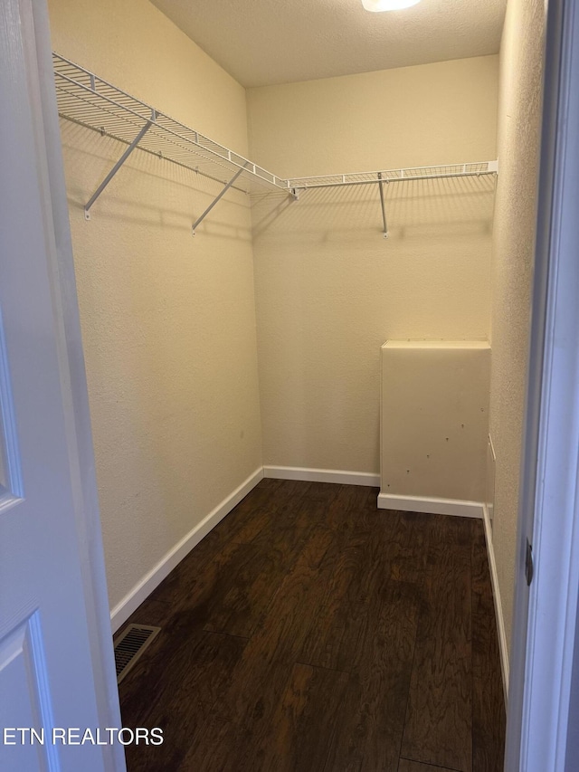 spacious closet with dark wood-style flooring and visible vents