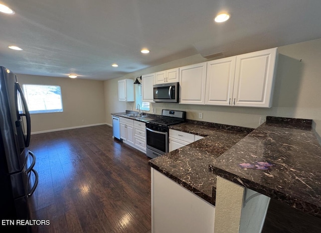 kitchen featuring stainless steel appliances, white cabinets, a peninsula, and dark wood-type flooring