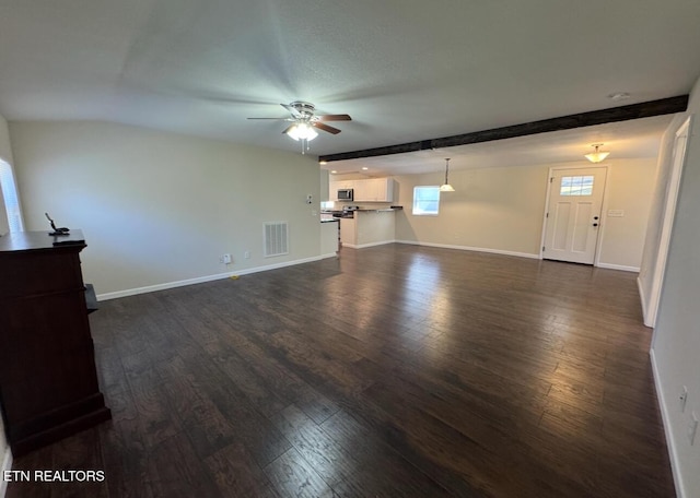 unfurnished living room with ceiling fan, visible vents, baseboards, beamed ceiling, and dark wood finished floors