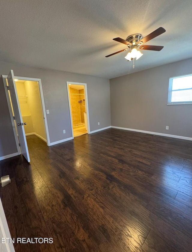 unfurnished room with a textured ceiling, ceiling fan, dark wood-style flooring, and baseboards