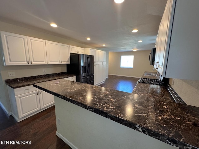 kitchen with dark wood-style floors, black refrigerator with ice dispenser, stainless steel microwave, and white cabinetry