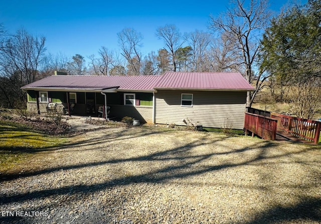 rear view of house with driveway and metal roof