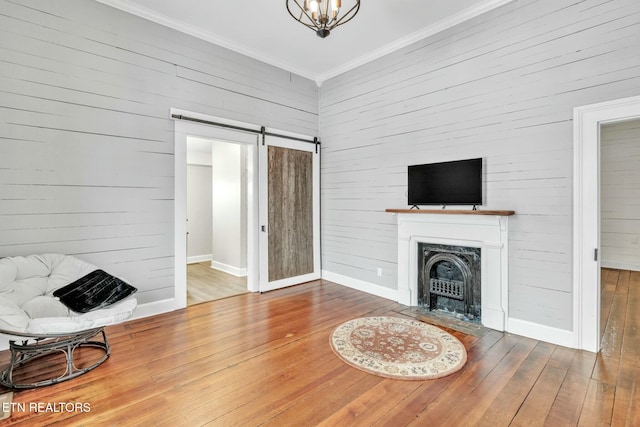 living room with crown molding, a barn door, and hardwood / wood-style floors