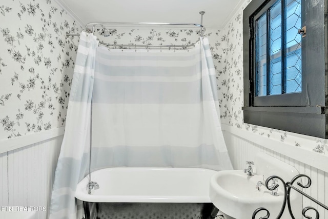 bathroom featuring shower / bath combination with curtain, ornamental molding, and sink