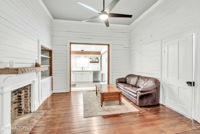 living room featuring wooden walls, sink, hardwood / wood-style floors, and ceiling fan