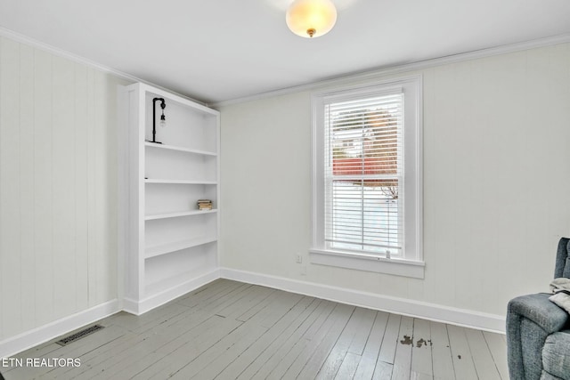 interior space featuring ornamental molding, a wealth of natural light, and light hardwood / wood-style flooring