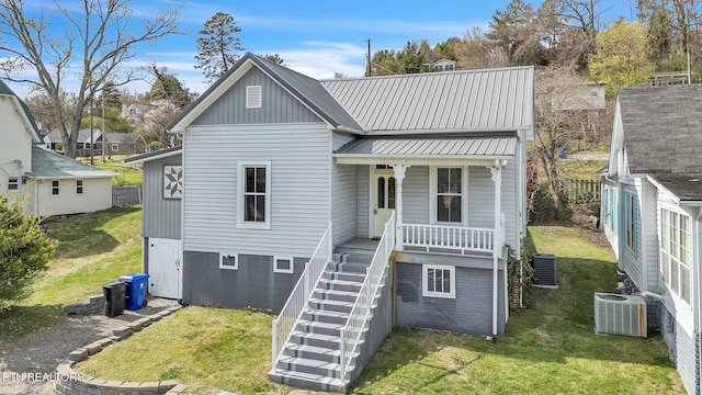 view of front of house with cooling unit, covered porch, a front lawn, and stairs
