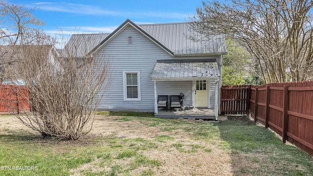 back of house featuring a lawn, metal roof, a fenced backyard, and a deck