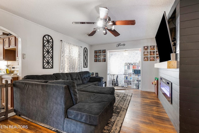 living room featuring ceiling fan, dark hardwood / wood-style floors, and a textured ceiling