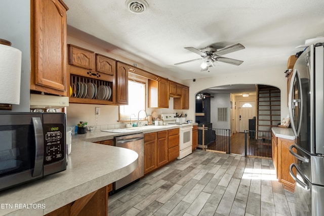 kitchen with a textured ceiling, ceiling fan, stainless steel appliances, and sink