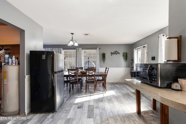 dining area featuring hardwood / wood-style flooring, water heater, and an inviting chandelier