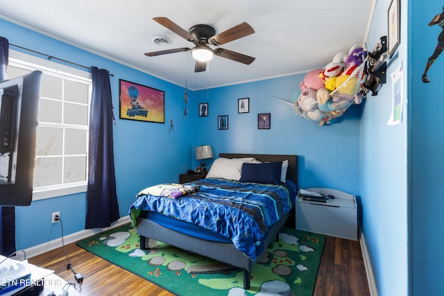 bedroom featuring ceiling fan, dark hardwood / wood-style flooring, crown molding, and multiple windows