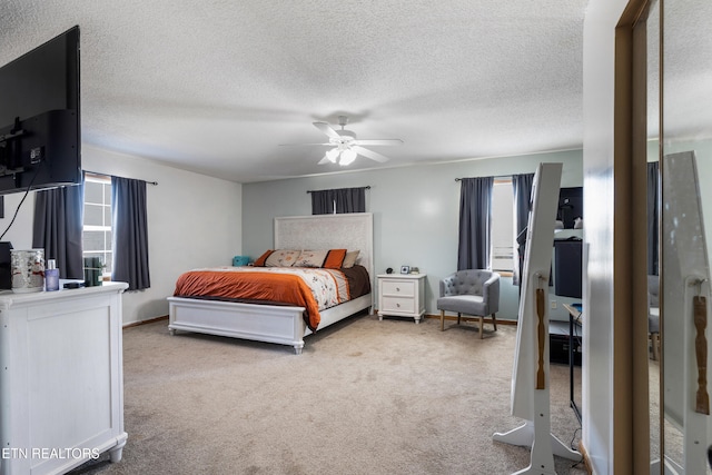 bedroom with ceiling fan, a textured ceiling, multiple windows, and carpet flooring