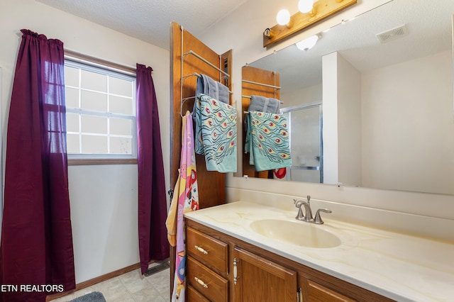 bathroom featuring vanity, a shower with door, and a textured ceiling