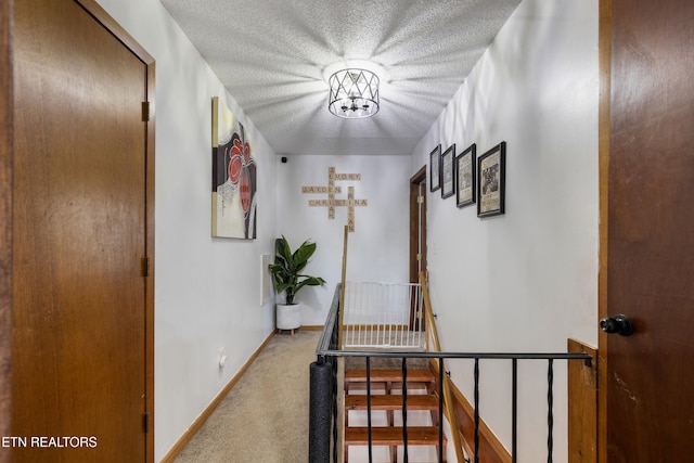 hall with a textured ceiling and carpet flooring