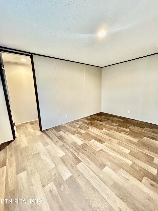 spare room featuring light wood-type flooring and a textured ceiling