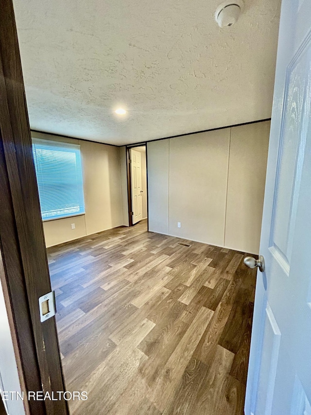 unfurnished room featuring a textured ceiling and light hardwood / wood-style flooring