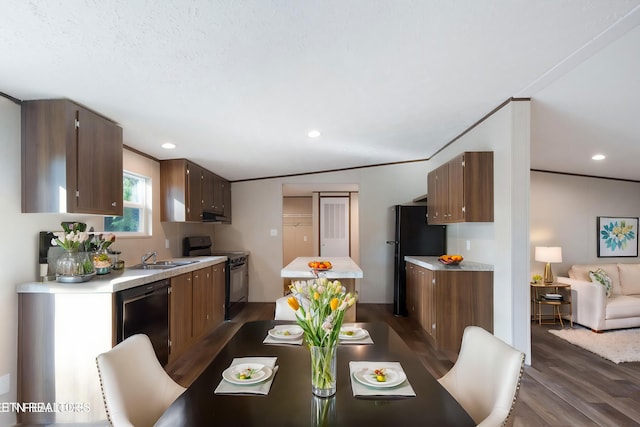 dining space featuring sink, a textured ceiling, dark hardwood / wood-style floors, and vaulted ceiling