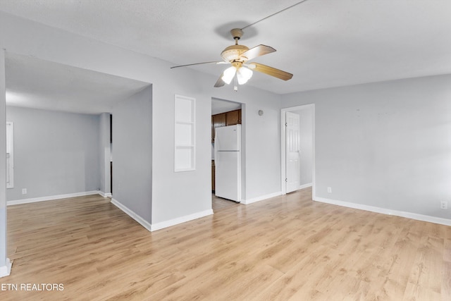 empty room with ceiling fan, light wood-type flooring, and a textured ceiling