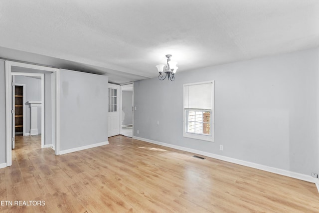 unfurnished room featuring a textured ceiling, a notable chandelier, and light hardwood / wood-style flooring