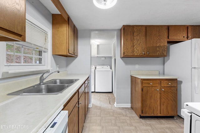 kitchen featuring white appliances, light parquet flooring, washing machine and dryer, and sink