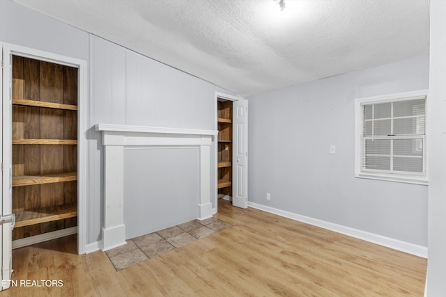 unfurnished bedroom featuring a textured ceiling, light hardwood / wood-style flooring, a closet, and vaulted ceiling