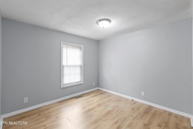 spare room with light wood-type flooring and a textured ceiling