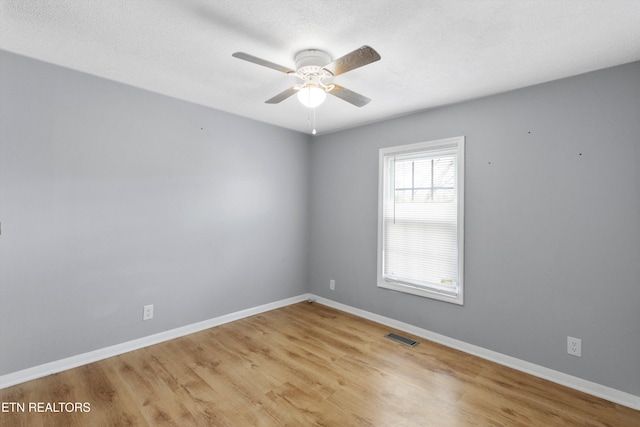 spare room featuring a textured ceiling, light wood-type flooring, and ceiling fan