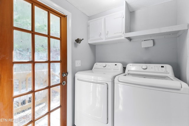 clothes washing area featuring cabinets and washer and clothes dryer