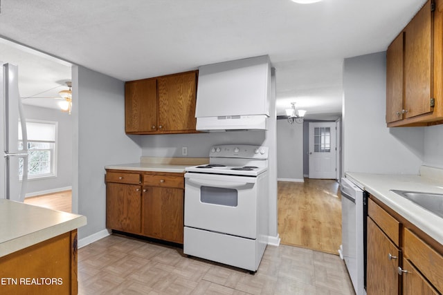 kitchen featuring white appliances, light parquet flooring, sink, and ceiling fan with notable chandelier