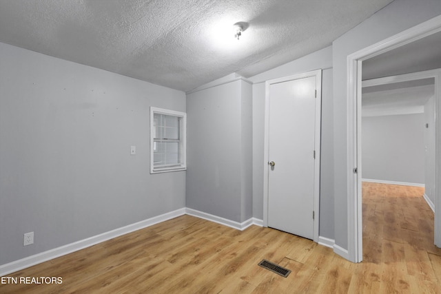 interior space with a textured ceiling, light hardwood / wood-style floors, and a closet