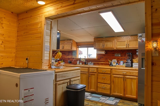 kitchen featuring wood walls, fridge, and sink