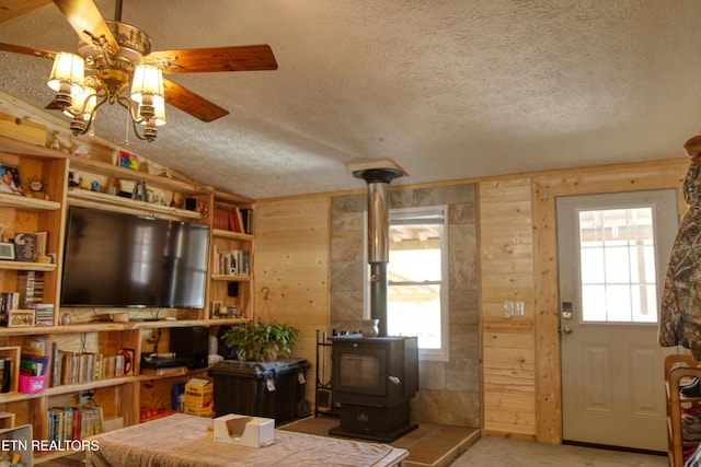 carpeted living room with a healthy amount of sunlight, a wood stove, and wood walls