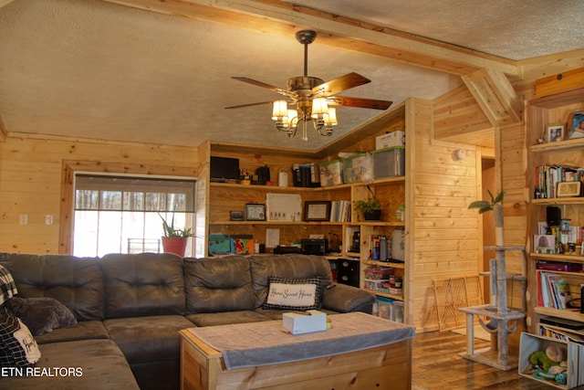 living room featuring ceiling fan, wood walls, lofted ceiling with beams, wood-type flooring, and a textured ceiling