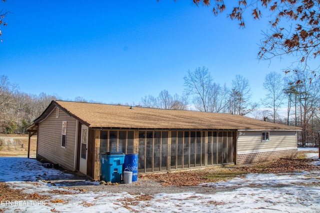 view of snowy exterior featuring a sunroom