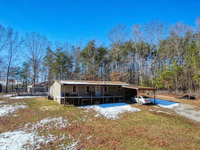 snow covered property featuring central AC unit and a carport