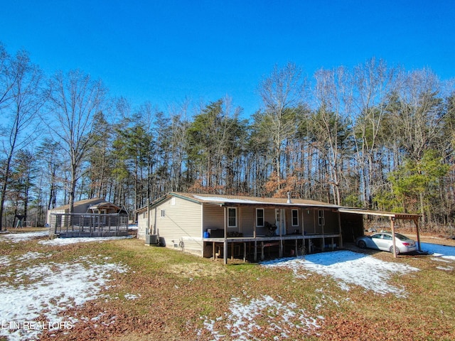 snow covered property featuring central air condition unit and a carport