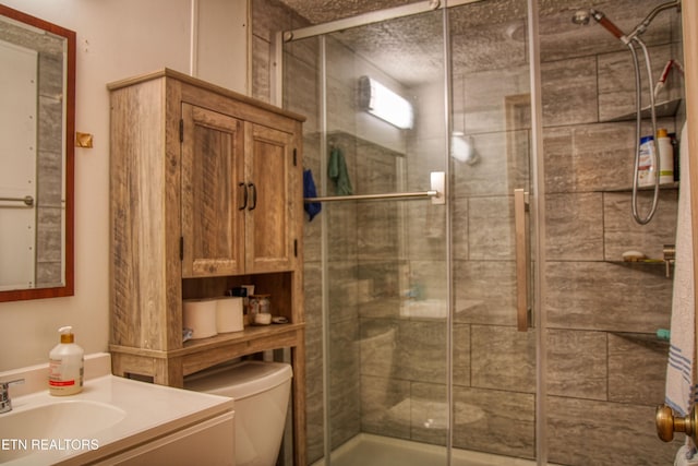 bathroom featuring toilet, vanity, and a shower with shower door