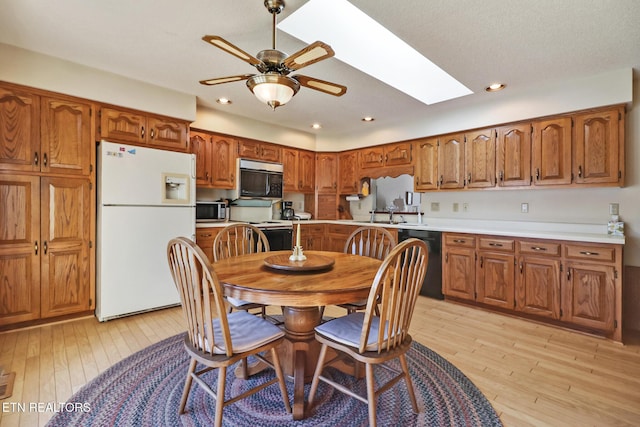 kitchen featuring a skylight, white appliances, light hardwood / wood-style flooring, and ceiling fan