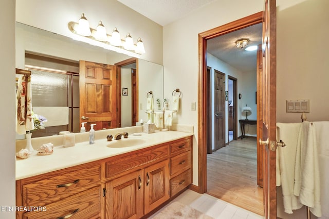 bathroom featuring a shower with door, vanity, hardwood / wood-style floors, and a textured ceiling