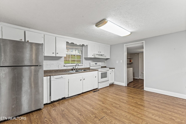 kitchen with white appliances, white cabinets, a textured ceiling, and sink