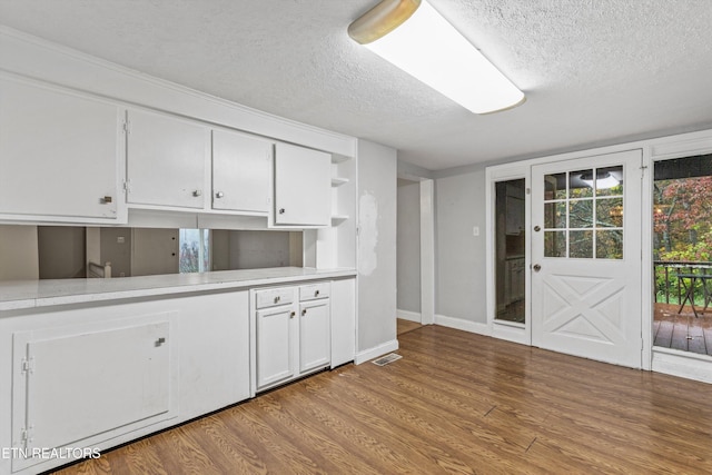 kitchen featuring light hardwood / wood-style floors, white cabinetry, and a textured ceiling