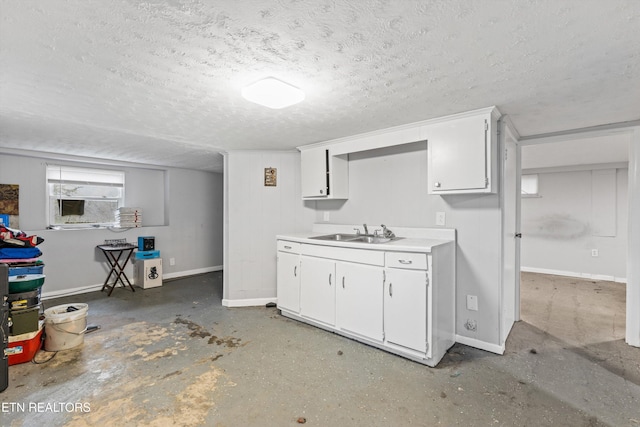 interior space featuring sink, white cabinetry, concrete floors, and a textured ceiling