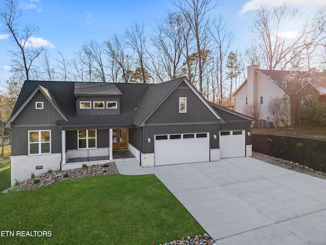 view of front of property with covered porch, a garage, and a front lawn