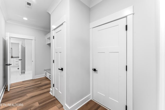 corridor with dark wood-type flooring and ornamental molding