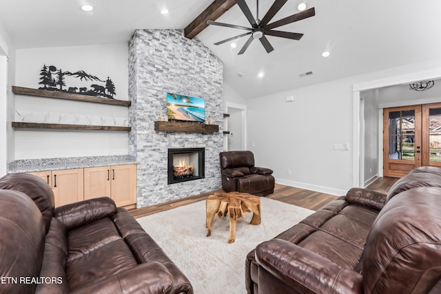 living room with ceiling fan, lofted ceiling with beams, a stone fireplace, french doors, and dark hardwood / wood-style flooring