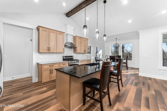 kitchen featuring beamed ceiling, an island with sink, dark stone countertops, sink, and stainless steel range with gas stovetop